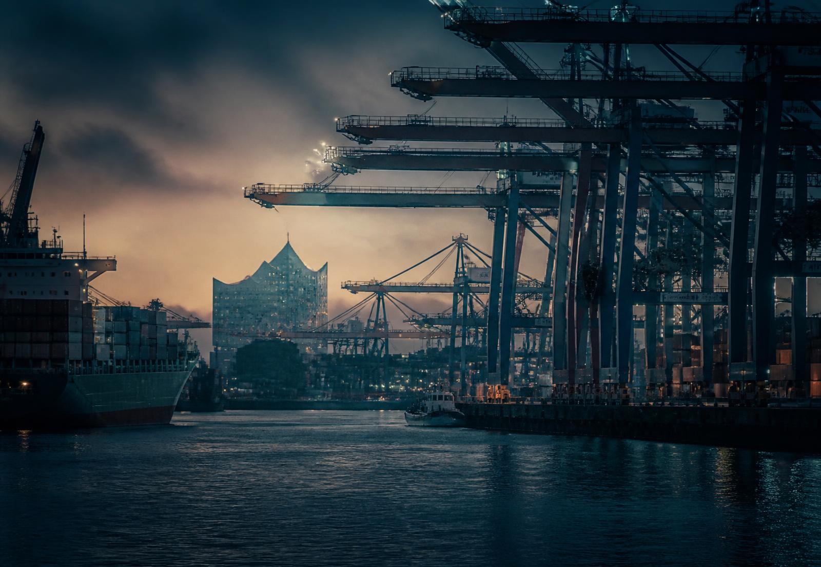 Hamburger Hafen mit Containerbrücken und Elbphilharmonie in der Abenddämmerung